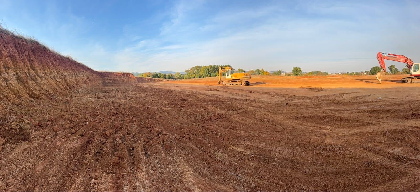 Panorama of the levelled 300 MW pad with excavators, October 2026